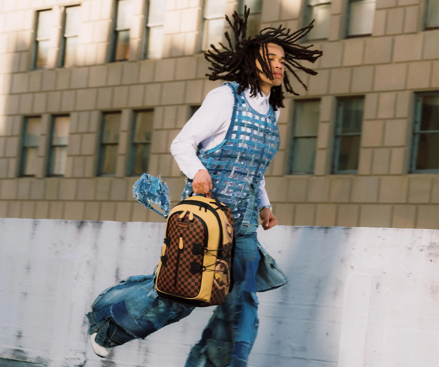 A model holding a checked backpack against a city building