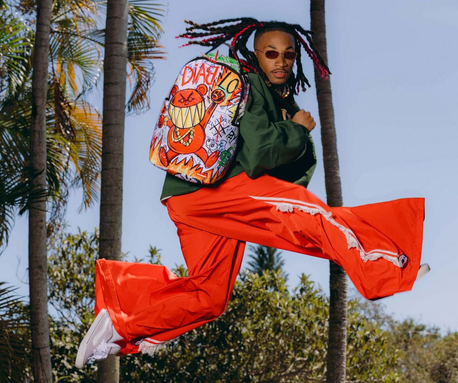 A model carrying a colorful printed backpack in an outdoor streetwear scene